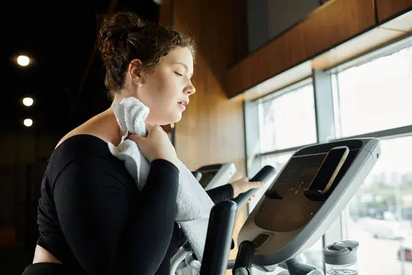 Une femme de plus grande taille fait de l'exercice sur une machine, embrassant avec confiance son voyage de remise en forme dans la salle de gym. — Photo de stock