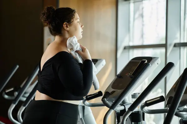 A young woman pauses on the treadmill, towel in hand, reflecting on her workout journey in the gym. — Stock Photo