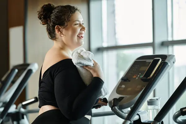 A young woman smiles while exercising on a machine, showcasing her confidence and body positivity. — Stock Photo