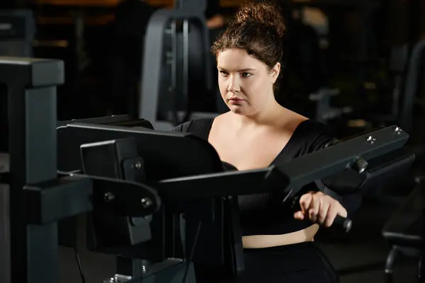 Une femme de taille plus s'engage dans une séance d'entraînement au gymnase, mettant en valeur la positivité et la détermination du corps. — Photo de stock