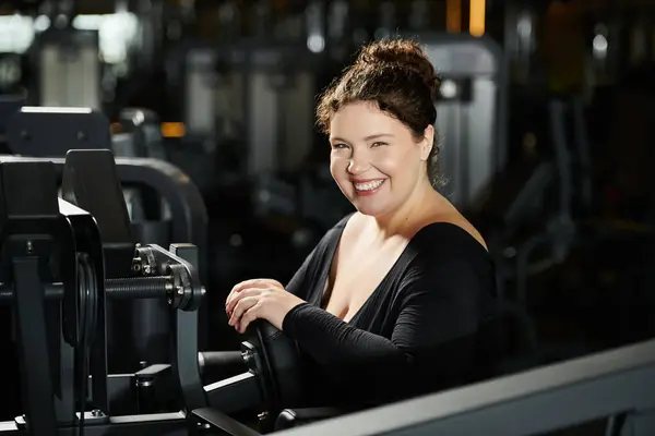 Eine junge Frau umarmt Körperpositivität und genießt ihre Trainingseinheit im Fitnessstudio mit Zuversicht. — Stockfoto