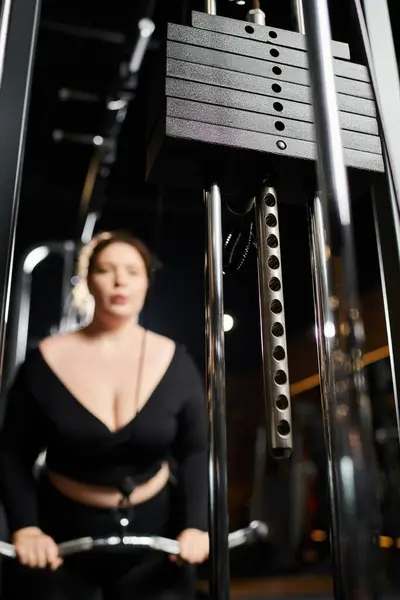 A confident plus-size woman exercises in active wear, promoting body positivity and fitness in a vibrant gym. — Stock Photo