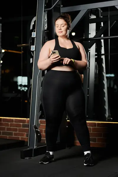 A confident young woman embraces her strength, taking a moment to check her phone during an empowering workout. — Stock Photo