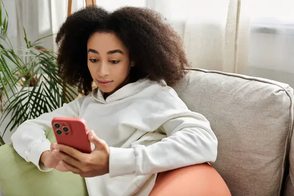 A young woman enjoys a relaxed day indoors, immersed in her phone while lounging comfortably. — Stock Photo