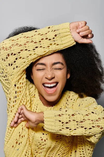 A young woman in a yellow sweater expresses joy and excitement with a bright smile. — Stock Photo