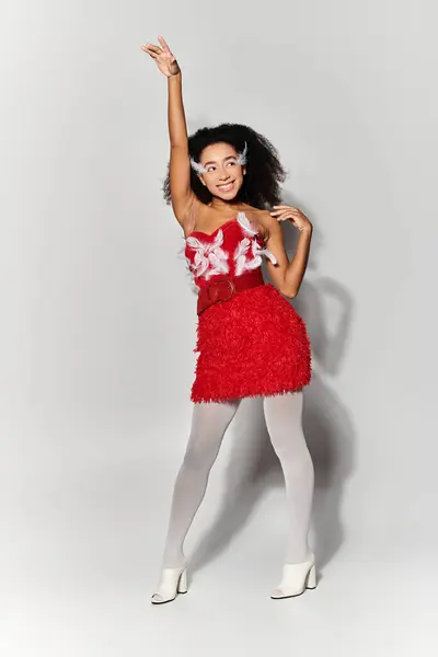 A stylish young woman showcases her bold red ensemble while striking a playful pose on a neutral background. — Stock Photo