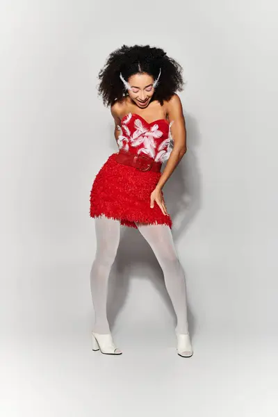A young woman showcases her style and joy in a striking red ensemble adorned with feathers. — Stock Photo