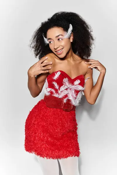 A young woman joyfully poses in a striking red outfit adorned with feathers, exuding confidence and style. — Stock Photo
