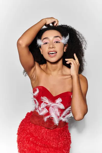A stylish young woman showcases her vibrant red ensemble with feathers while smiling confidently. — Stock Photo