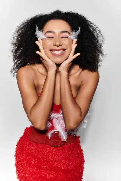 A young woman with curly hair radiates happiness while posing in a striking red ensemble. — Stock Photo