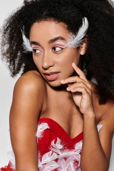 A young woman with curly hair stylishly showcases her striking red outfit adorned with feathers. — Stock Photo