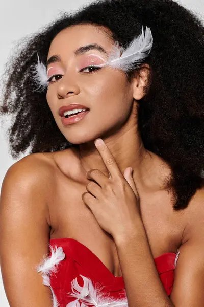 A young African American woman poses confidently in a stylish red outfit adorned with feathers. — Stock Photo