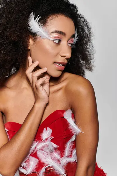 A stylish young woman showcases her unique red feathered dress, exuding confidence in a modern setting. — Stock Photo