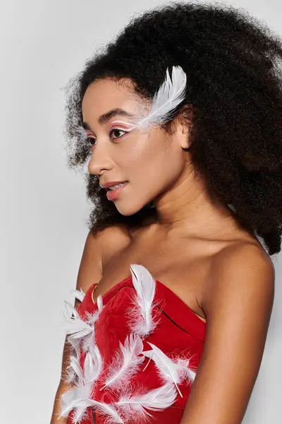 A stylish woman with curly hair showcases her chic red ensemble decorated with feathers. — Stock Photo