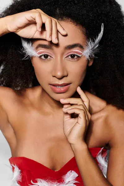 A young woman showcases her style in a bold red outfit adorned with feathers, while exuding confidence. — Stock Photo