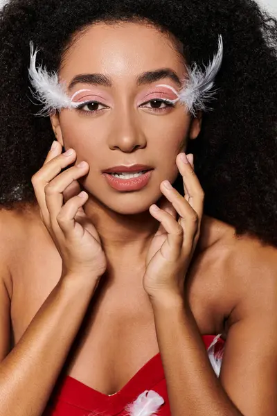 Uma jovem afro-americana em um conjunto vermelho impressionante posa graciosamente com penas brincalhão. — Fotografia de Stock