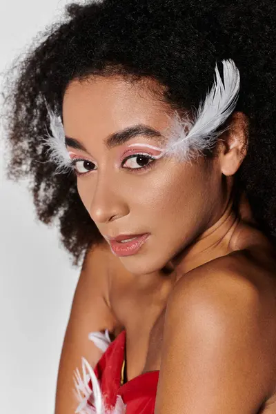 Une jeune femme dans un superbe ensemble rouge, orné de plumes, met en valeur son style avec confiance. — Photo de stock