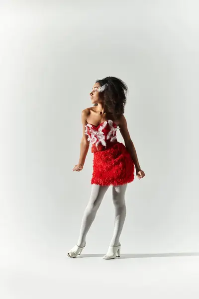 A young woman with curly hair exudes confidence, showcasing her stylish red ensemble on a minimalist background. — Stock Photo