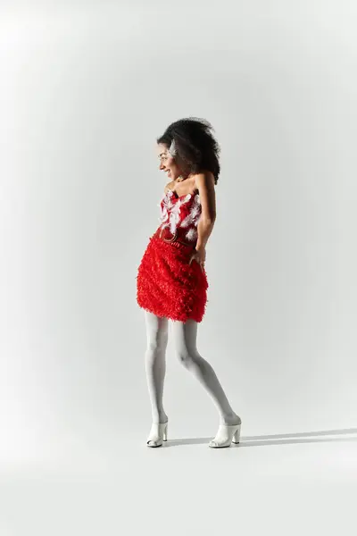 A confident young woman showcases her unique red ensemble while striking a playful pose. — Stock Photo