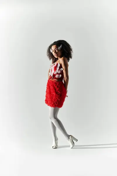 Una joven mujer irradia elegancia en un conjunto de plumas rojas, mostrando su estilo único y confianza. — Stock Photo