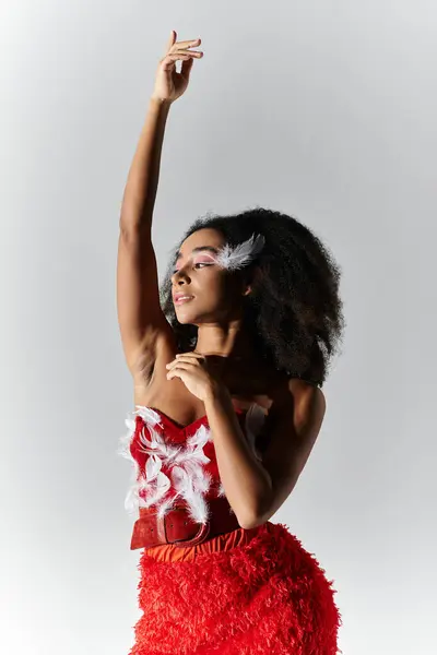 A confident young woman showcases her style in a vibrant red ensemble adorned with feathers. — Stock Photo