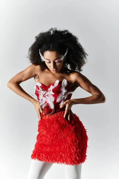 A young woman showcases her style in a striking red attire adorned with feathers, exuding confidence. — Stock Photo