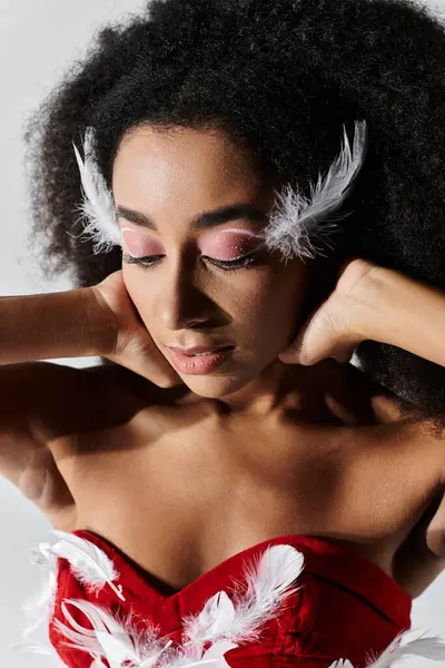 A young woman poses gracefully in a striking red outfit adorned with feathers, radiating elegance. — Stock Photo