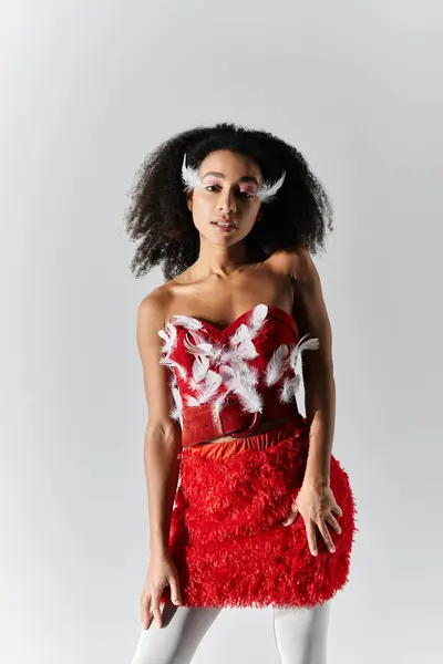 The young woman showcases her fashionable style, radiating confidence in a vibrant red attire adorned with feathers. — Stock Photo