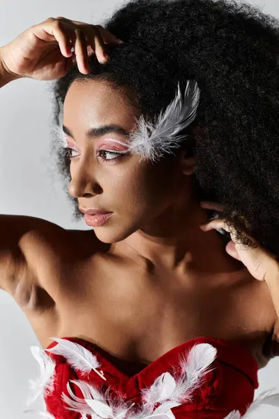 A stylish young woman gracefully poses in a vibrant red feathered outfit, exuding confidence and artistry. — Stock Photo