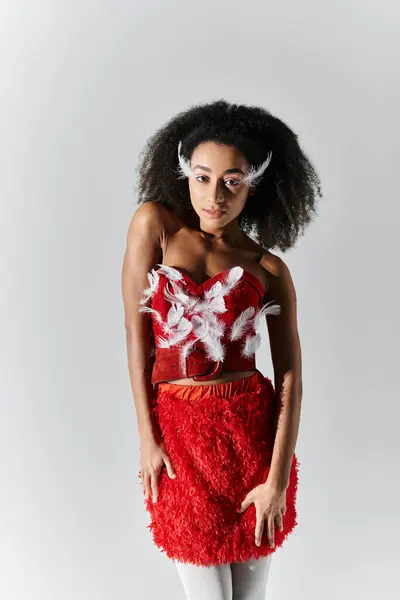 A stylish young woman showcases her confident pose in a vibrant red ensemble adorned with feathers. — Stock Photo