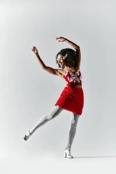 A spirited young woman showcases her style and grace in a striking red ensemble with feathers. — Stock Photo