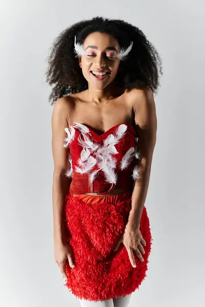 A spirited young woman beams in a striking red outfit adorned with fluffy feathers. — Stock Photo