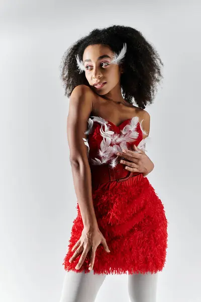 A young woman showcases her style in a striking red ensemble adorned with feathers, exuding confidence. — Stock Photo