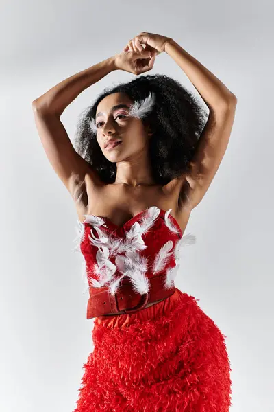 A confident young woman showcases her unique red outfit adorned with feathers, exuding grace and style. — Stock Photo