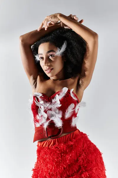 A young woman shows elegance and confidence in a vibrant red ensemble adorned with feathers. — Stock Photo