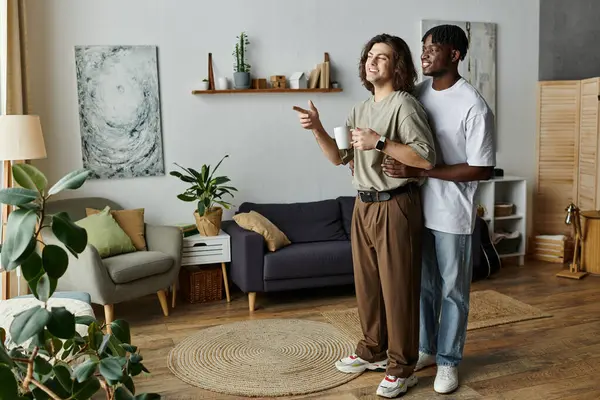 A happy gay couple embraces warmly, sharing laughter and love in their inviting living space. — Stock Photo