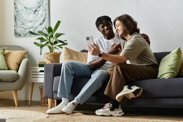 Due partner sorridono e si divertono abbracciandosi su un comodo divano. — Foto stock