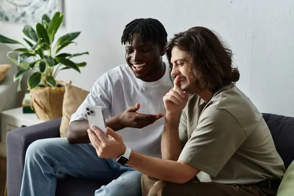 A couple shares laughter and smiles while enjoying time together at home on their phone. — Stock Photo