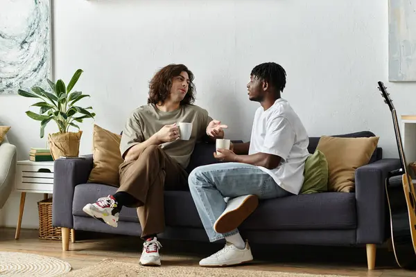 A loving couple engages in a warm conversation while sipping coffee on a cozy couch. — Stock Photo