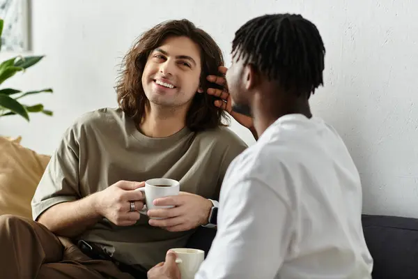 Dos parejas disfrutan del afecto y la alegría, abrazándose entre sí con bebidas calientes en casa. — Stock Photo