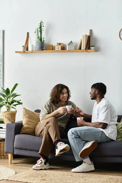 Two partners share a tender moment over coffee in their cozy living space filled with plants. — Stock Photo