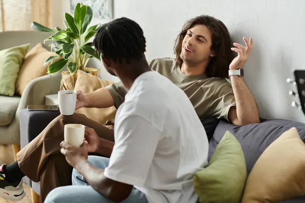 Two partners relax together, enjoying deep conversation and warm drinks in their cozy living space. — Stock Photo