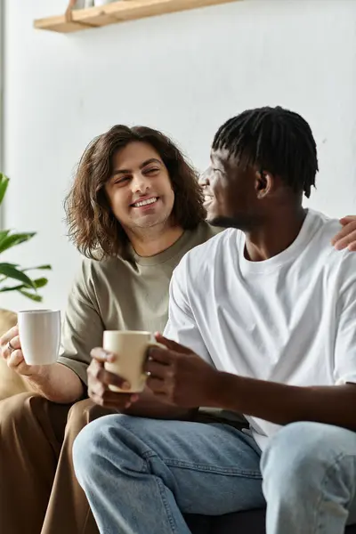 Deux partenaires se sourient chaleureusement tout en sirotant du café dans leur salon confortable. — Photo de stock