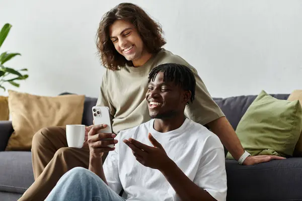 A joyful couple relaxes on their couch, sharing smiles while using their phone together. — Stock Photo