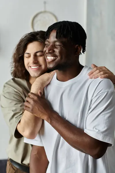 Dois parceiros abraçam calorosamente em casa, compartilhando risos e amor em um momento pacífico juntos. — Fotografia de Stock