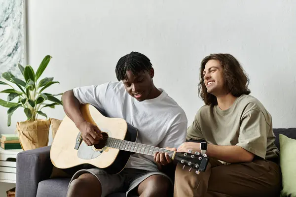 Two partners share a joyful afternoon at home strumming a guitar and laughing. — Stock Photo