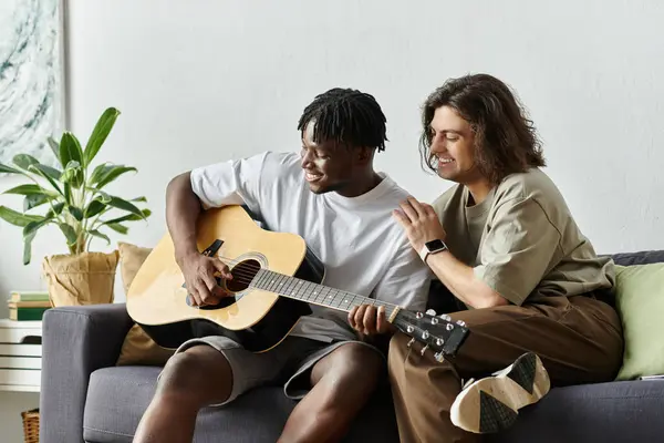 Dois parceiros compartilham um momento alegre, tocando guitarra e se divertindo em sua casa. — Fotografia de Stock