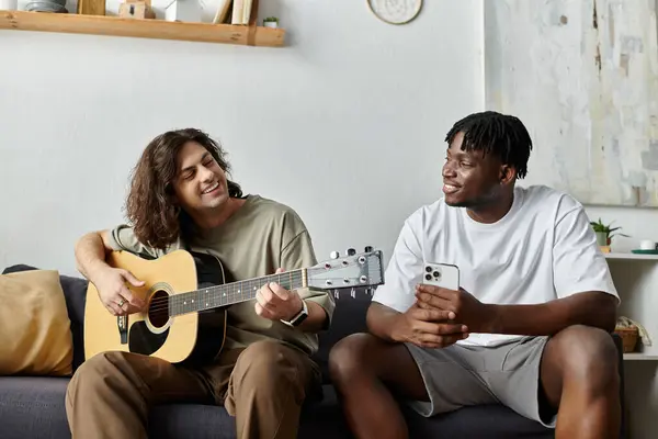 Dois parceiros desfrutam de uma noite relaxada, tocando guitarra e compartilhando momentos alegres em casa. — Fotografia de Stock