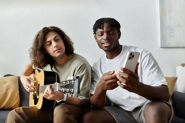Dos parejas disfrutan de un momento acogedor juntos, con uno tocando la guitarra y el otro compartiendo una sonrisa. - foto de stock