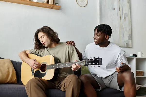 Dois parceiros compartilham um momento terno enquanto tocam guitarra e compartilham risos em sua sala de estar. — Fotografia de Stock